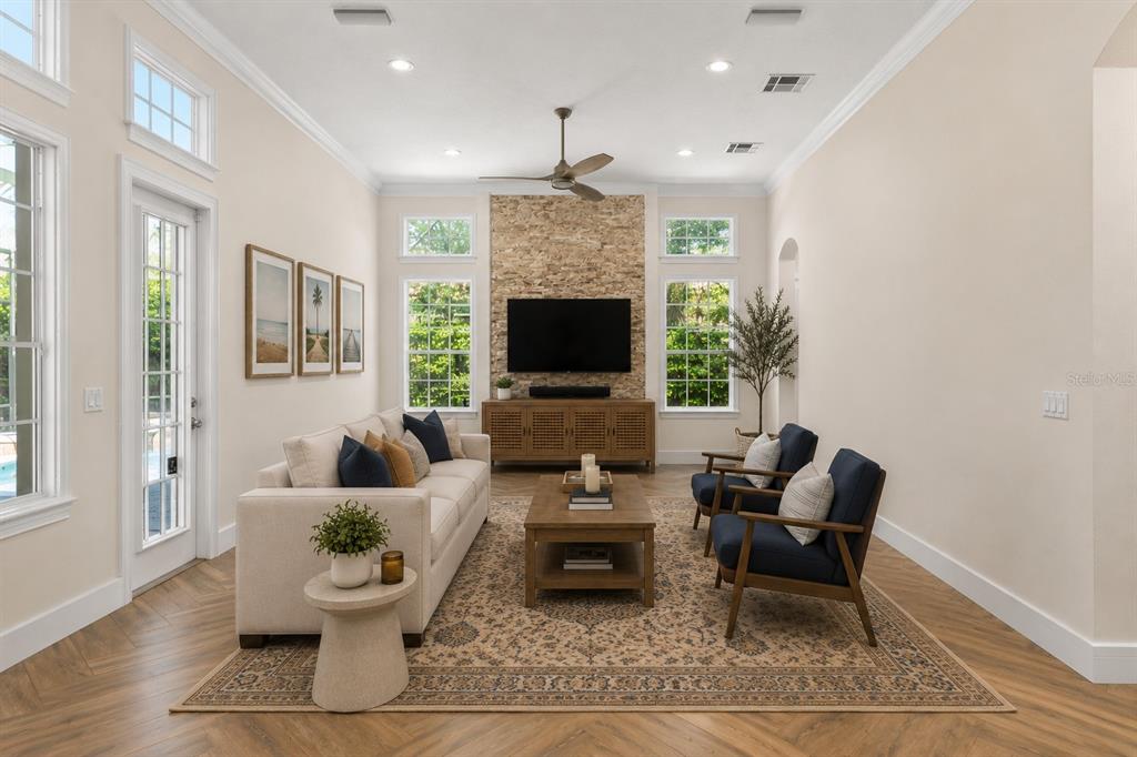 A living room features a stone fireplace, a beige sofa, two armchairs, and wood flooring — 8351 BOWDEN WAY, WINDERMERE, FL