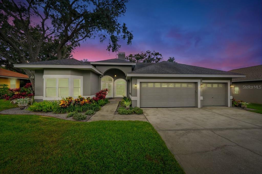 A single-story house with a gray exterior, a three-car garage, and a landscaped front yard — 700 WESTFIELD COURT, DUNEDIN, FL