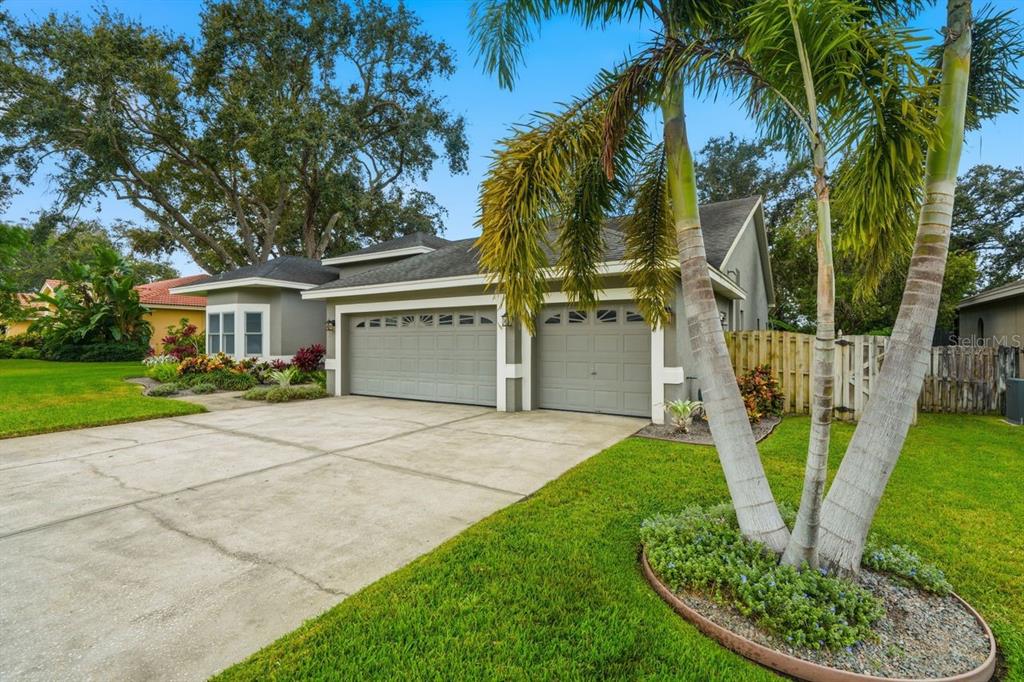 A single-story house with a two-car garage, a concrete driveway, and palm trees in front — 700 WESTFIELD COURT, DUNEDIN, FL