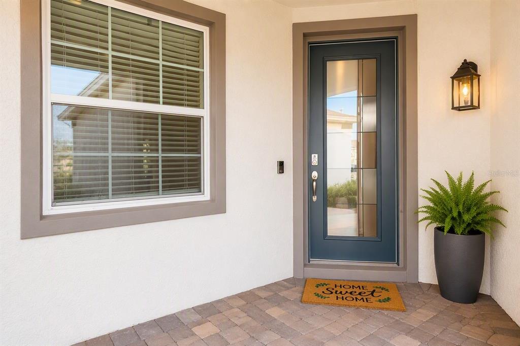 A front entryway features a blue glass-paneled door, a window, and a potted fern — 2756 SUMMER RETREAT LANE, KISSIMMEE, FL