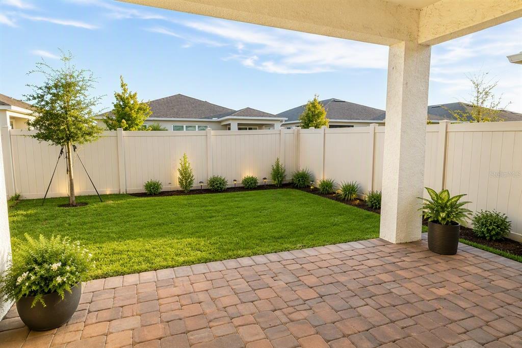 A paved patio overlooks a fenced backyard with a small lawn and young landscaping — 2756 SUMMER RETREAT LANE, KISSIMMEE, FL