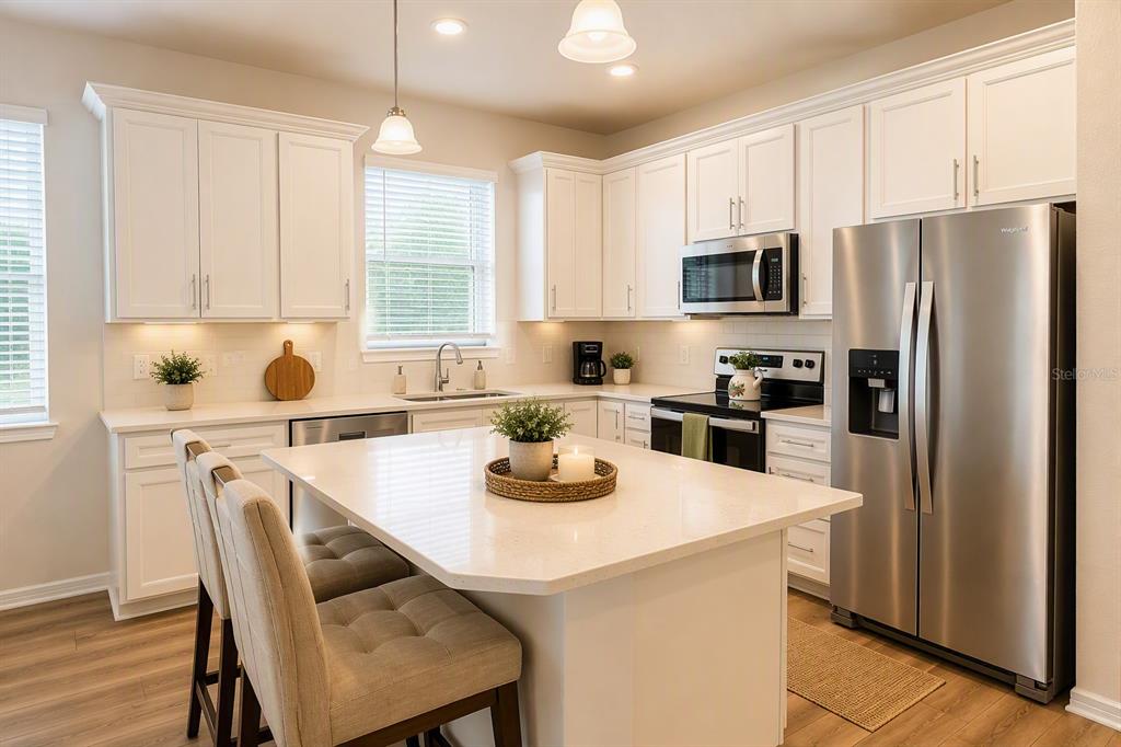 A modern kitchen features white cabinets, stainless steel appliances, and a central island with seating — 2756 SUMMER RETREAT LANE, KISSIMMEE, FL