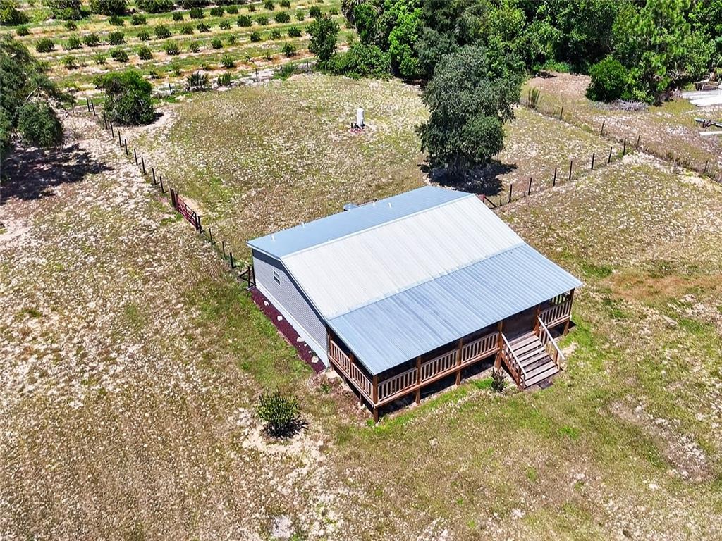 An aerial view shows a house with a metal roof and porch on rural land — 37647 JENNY LANE, EUSTIS, FL