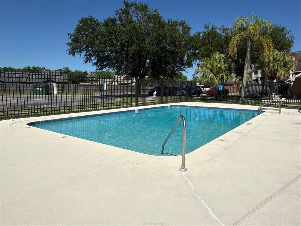 An outdoor swimming pool with a metal handrail is enclosed by a black metal fence — 3136 ENCLAVE CT, KISSIMMEE, FL
