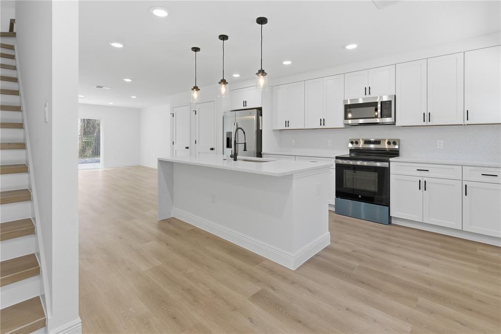 A modern kitchen features white cabinets, stainless steel appliances, a center island, and wood flooring — 727 CLEMSON DRIVE, ALTAMONTE SPRINGS, FL