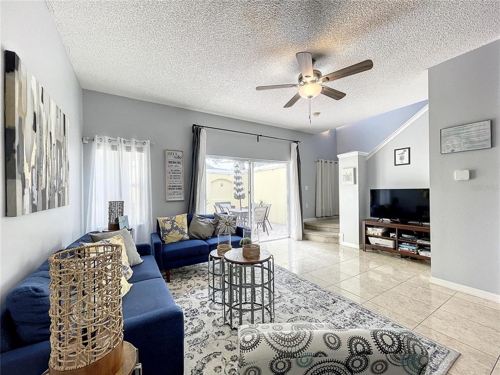 A living room features blue sofas, a patterned rug, tile flooring, and a sliding glass door — 123 POMPANO BEACH DRIVE, KISSIMMEE, FL
