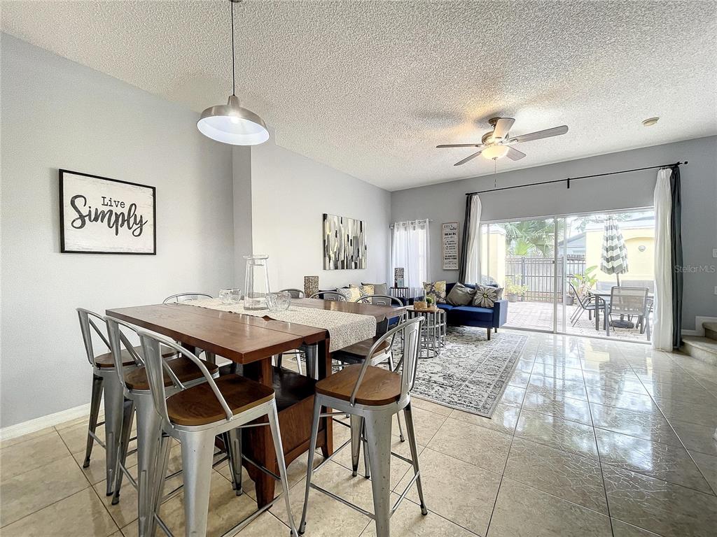 A dining area with metal stools and a pendant light opens into a living room — 123 POMPANO BEACH DRIVE, KISSIMMEE, FL
