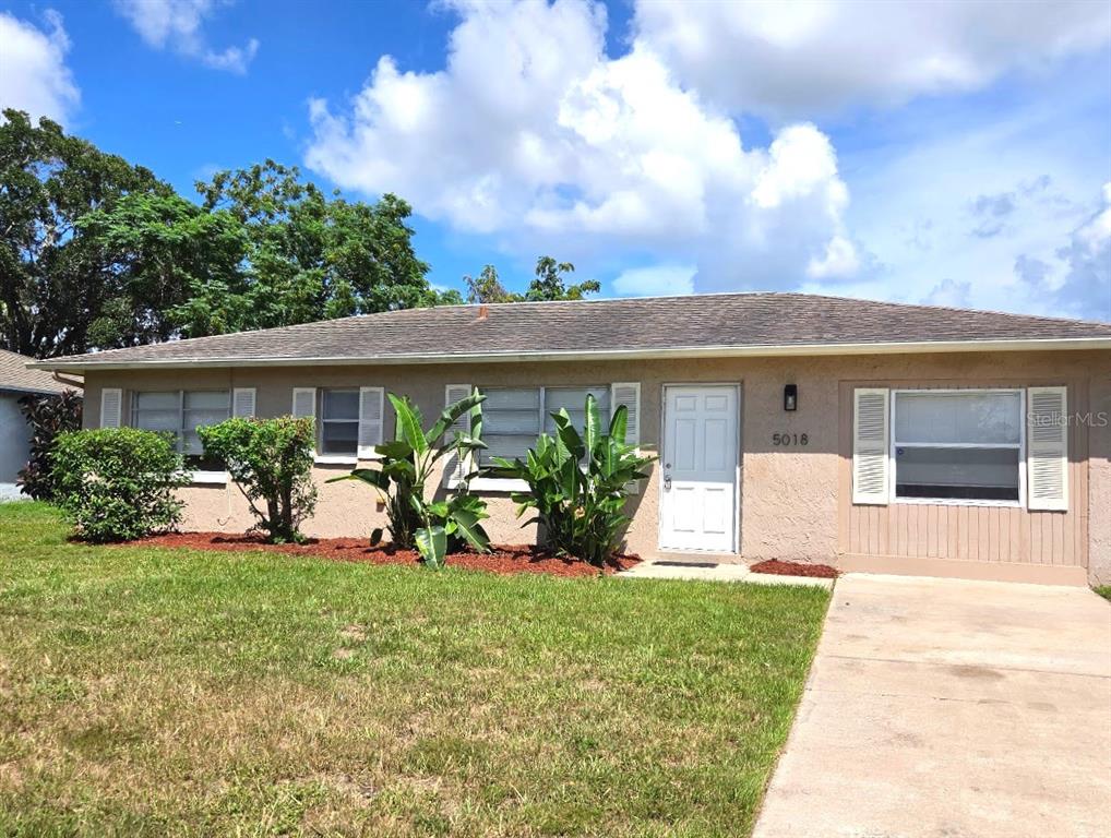 A single-story tan house with a white front door and a concrete driveway — 5018 LILLILEA LANE, NEW PORT RICHEY, FL