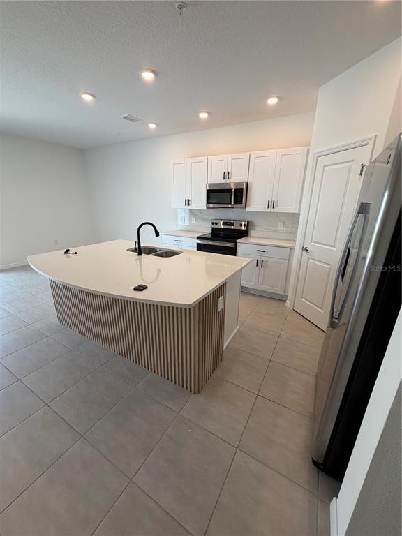 A kitchen features white cabinets, stainless steel appliances, and a slatted wood kitchen island — 4870 SPANGLE DRIVE, ST CLOUD, FL