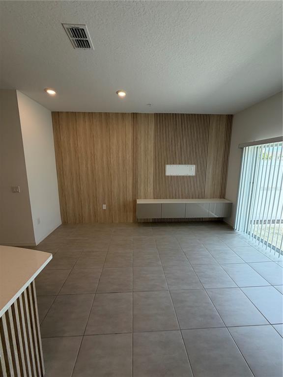 A living room features a wood-paneled accent wall, a floating cabinet, and large floor tiles — 4870 SPANGLE DRIVE, ST CLOUD, FL