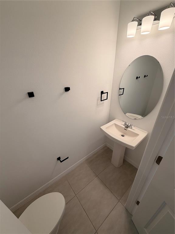 A small bathroom features a pedestal sink, an oval mirror, and matte black hardware — 4870 SPANGLE DRIVE, ST CLOUD, FL
