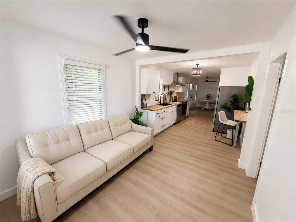 A living room with a beige sofa opens into a kitchen with white cabinets — 3505 N 16TH STREET, TAMPA, FL