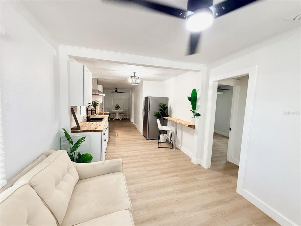 A living area flows into a kitchen with light wood floors and white cabinetry — 3505 N 16TH STREET, TAMPA, FL