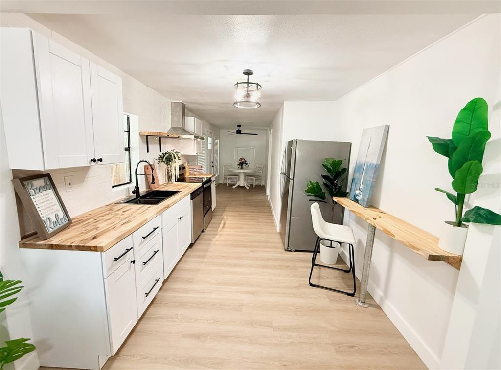 A galley kitchen features white cabinets, butcher block countertops, stainless appliances, and a breakfast bar — 3505 N 16TH STREET, TAMPA, FL