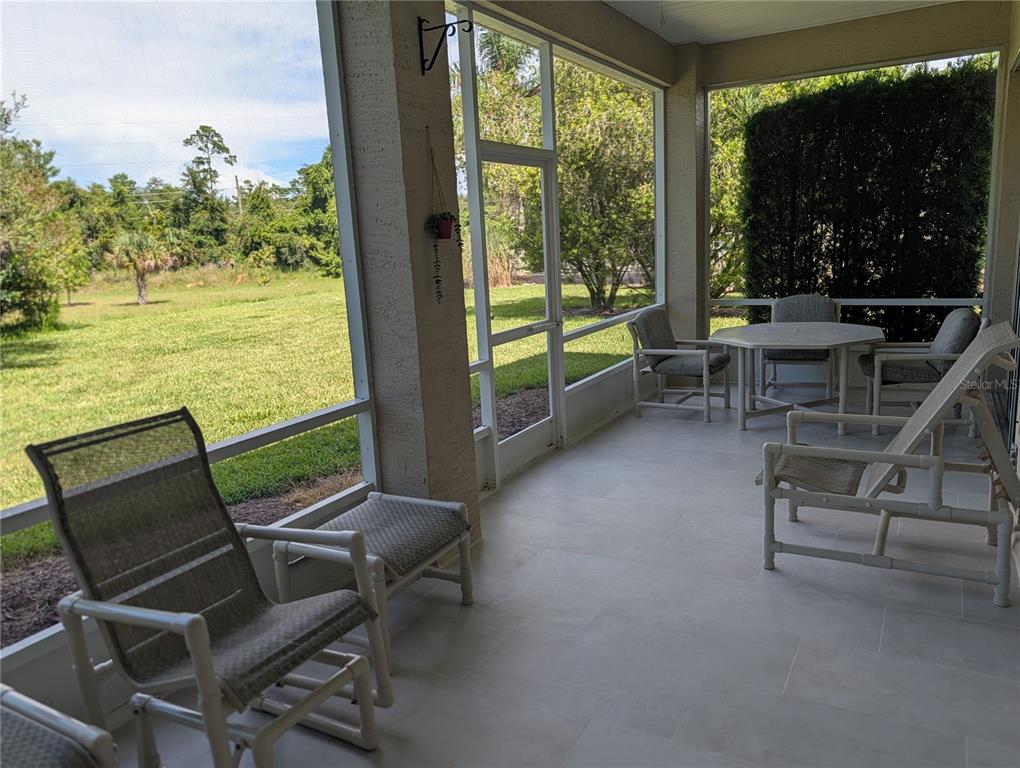 A view of a grassy backyard and trees from a screened-in porch — 1315 ELLI CIRCLE, ORMOND BEACH, FL
