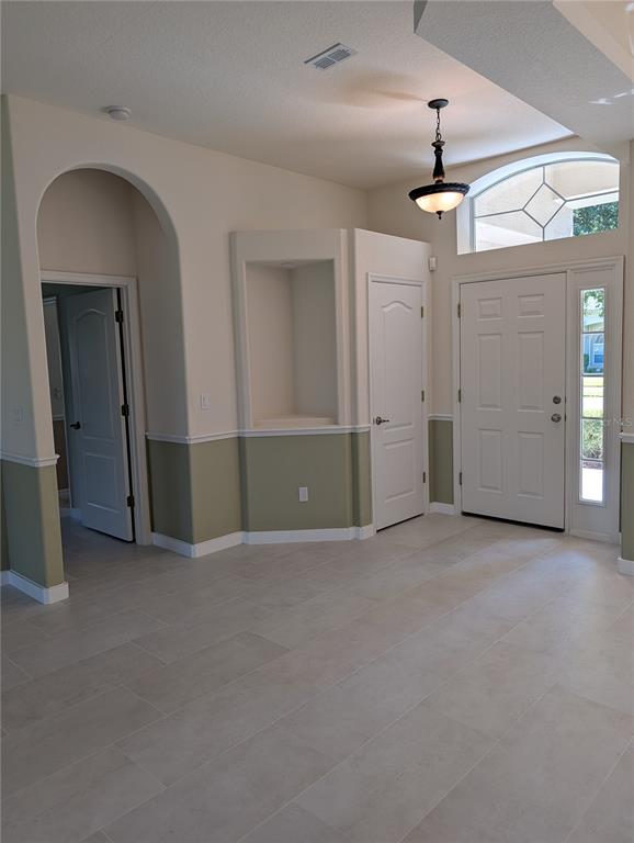 A grassy yard features a large tree, palm bushes, and a corner of a house — 1315 ELLI CIRCLE, ORMOND BEACH, FL