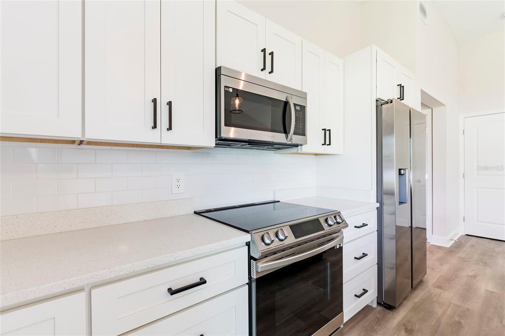 A kitchen features white cabinets, stainless steel appliances, a subway tile backsplash, and light countertops — 9808 SE 159TH STREET, SUMMERFIELD, FL