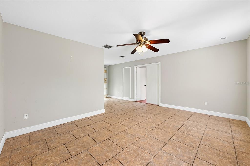 An empty room with beige walls, tile flooring, and a ceiling fan — 6045 WEDGEWOOD CIRCLE, ORLANDO, FL