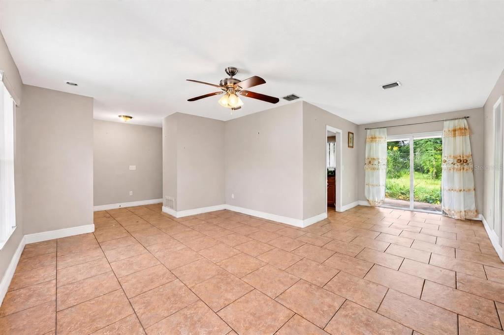 An empty room features light-colored walls, tile flooring, a ceiling fan, and sliding glass doors — 6045 WEDGEWOOD CIRCLE, ORLANDO, FL