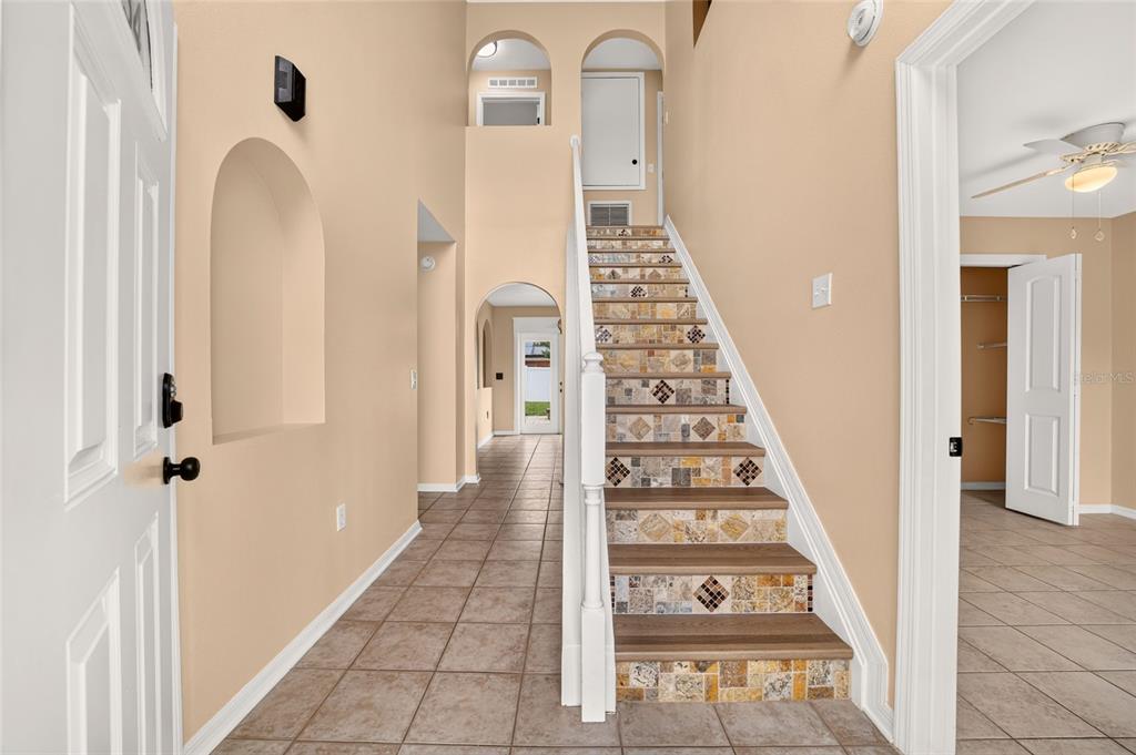 A foyer features tiled floors, a staircase with decorative risers, and an arched hallway — 6934 SW 129TH STREET, OCALA, FL
