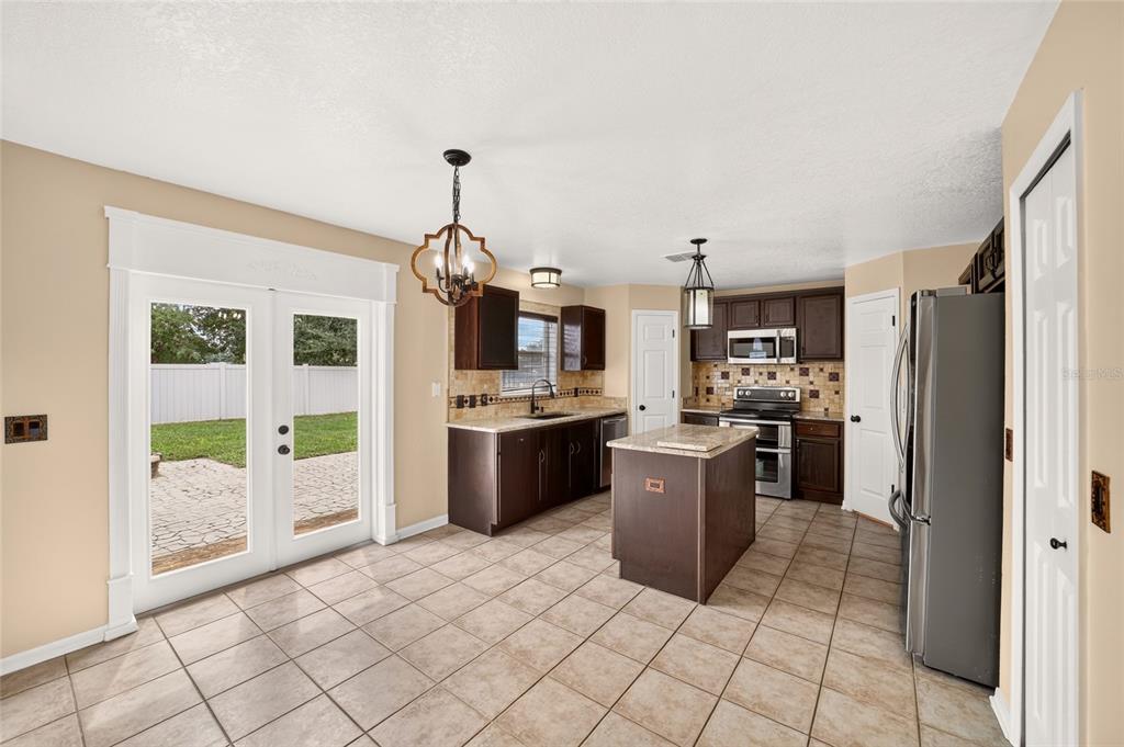 A kitchen with dark wood cabinets, a center island, tile flooring, and glass patio doors — 6934 SW 129TH STREET, OCALA, FL