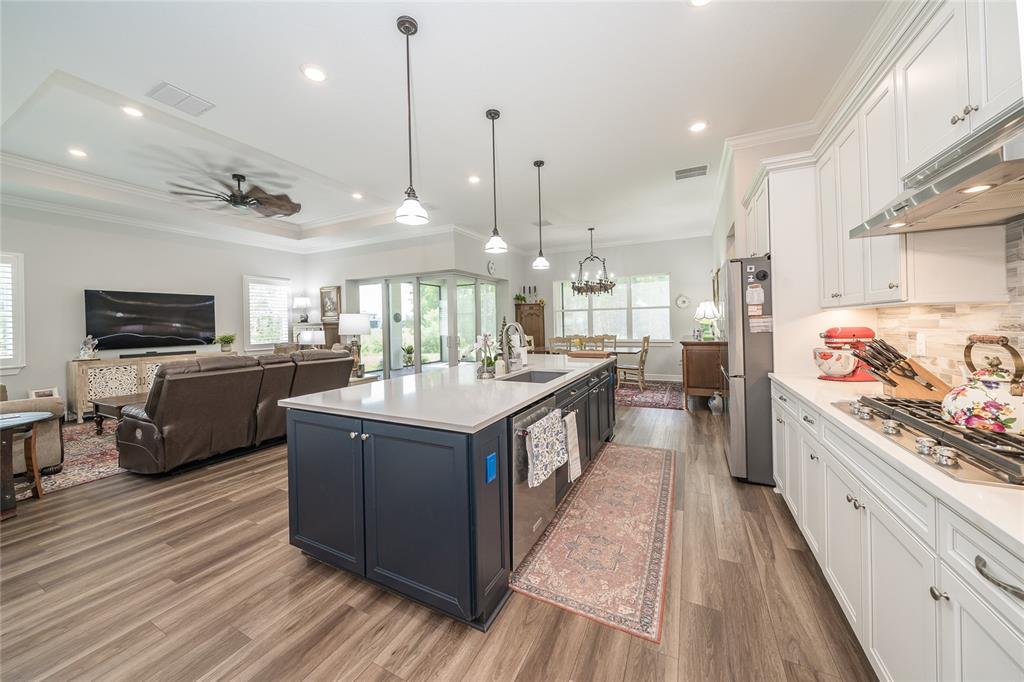 A kitchen with a dark blue island and white cabinets opens into a living room — 18793 HORIZON VIEW POINT, LAND O LAKES, FL