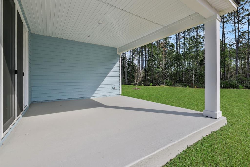 A covered concrete patio with light blue siding and a white support pillar overlooks grass — 333 BROOK FOREST DRIVE, ST AUGUSTINE, FL