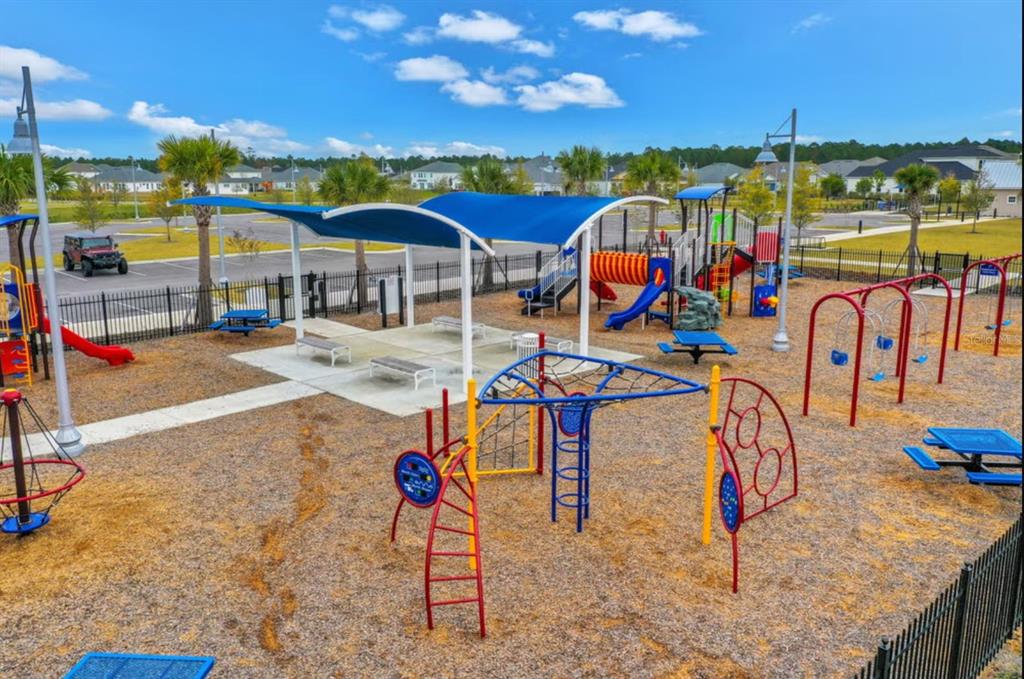 A colorful outdoor playground features climbing structures, slides, swings, and a shaded seating area — 333 BROOK FOREST DRIVE, ST AUGUSTINE, FL