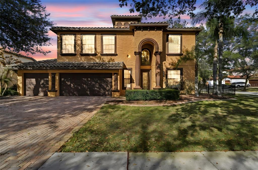 A two-story stucco house with a tile roof, arched entryway, and a brick paver driveway — 119 ELISSAR DRIVE, DEBARY, FL