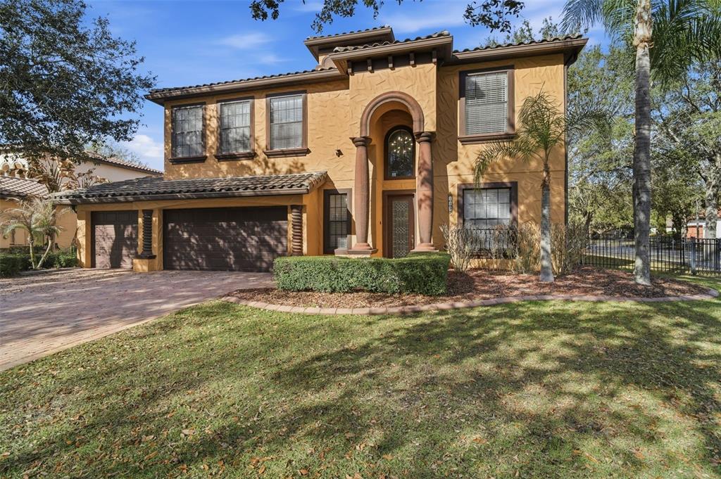 A two-story stucco house with a tile roof, arched entryway, and attached garage — 119 ELISSAR DRIVE, DEBARY, FL