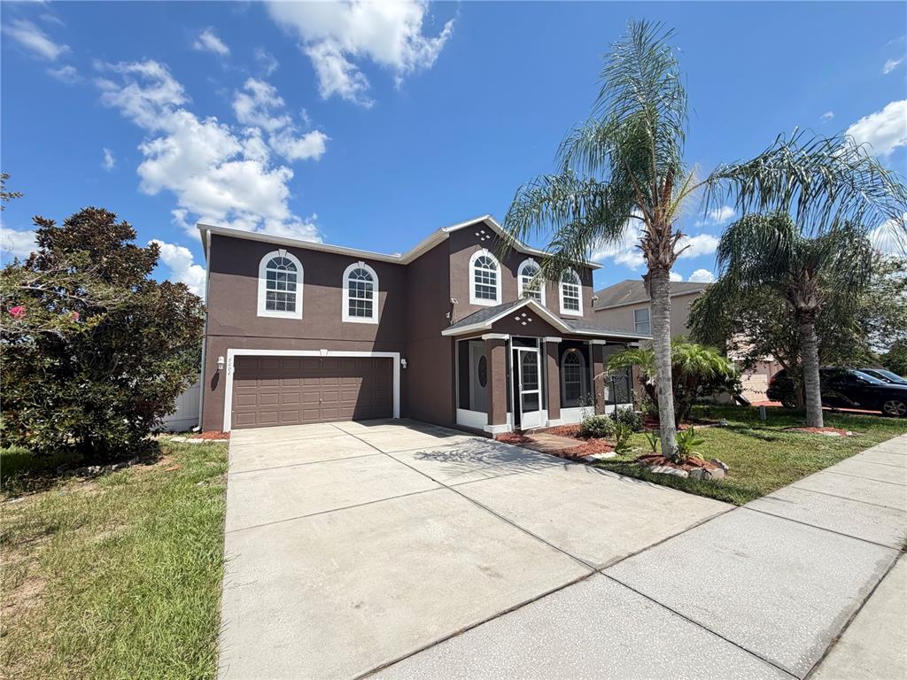 A two-story brown house features a two-car garage, arched windows, and a screened front entryway — 5604 ROYAL HILLS DRIVE, WINTER HAVEN, FL