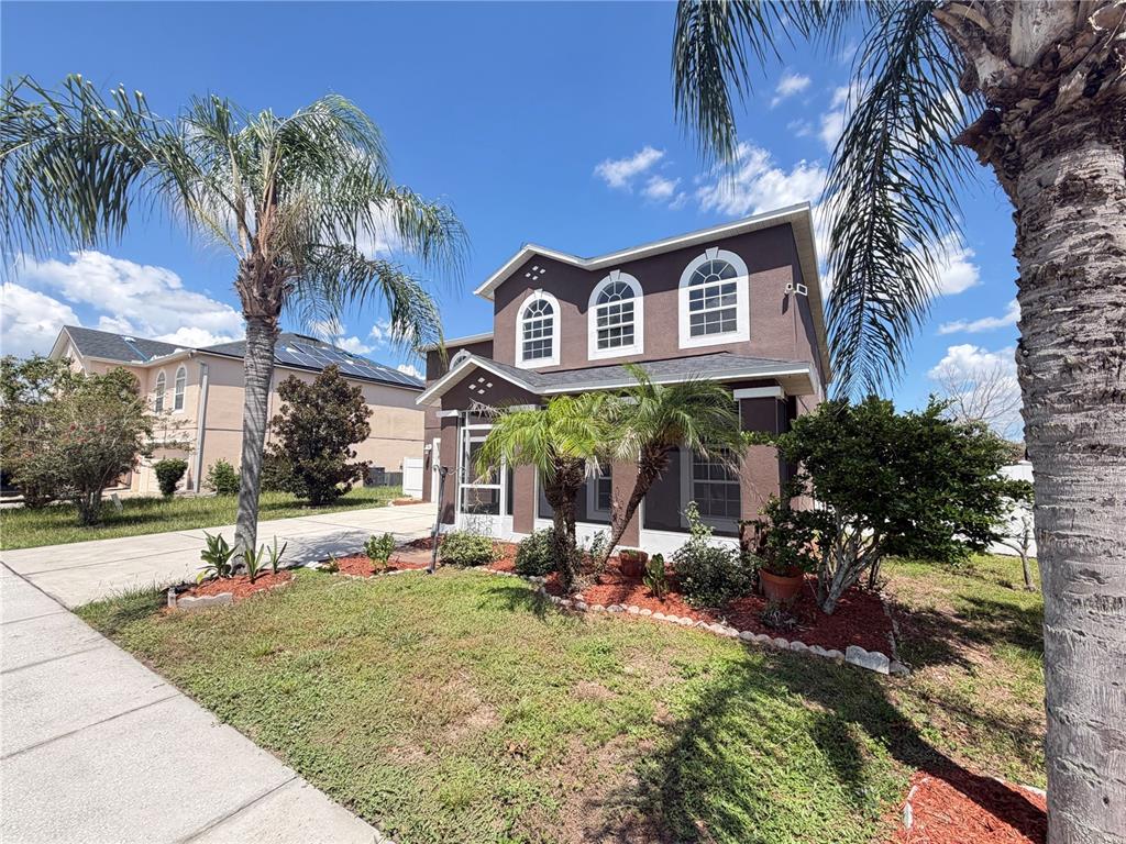 A two-story brown house with a palm tree in the front yard under a blue sky — 5604 ROYAL HILLS DRIVE, WINTER HAVEN, FL