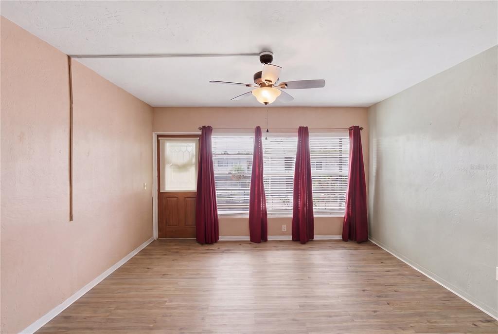 A room with light wood-look flooring, a ceiling fan, and a door leading outside — 4325 58TH WAY N UNIT 1525, KENNETH CITY, FL