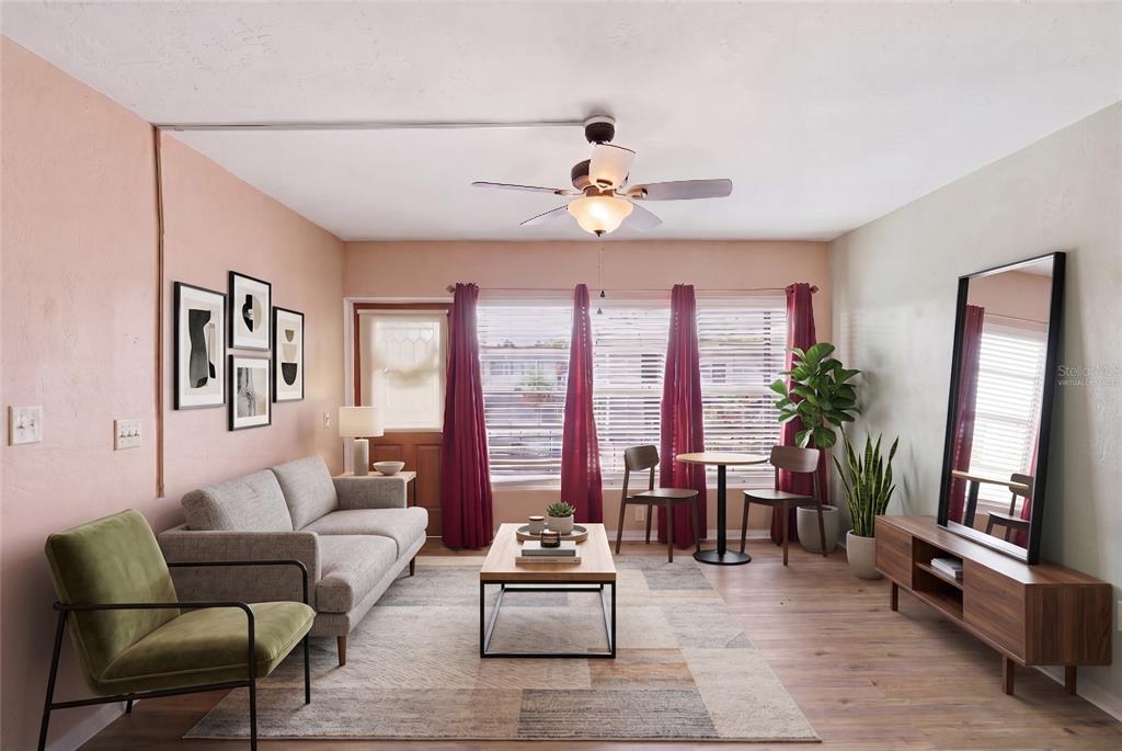 A living room features a grey sofa, green armchair, wood coffee table, and red curtains — 4325 58TH WAY N UNIT 1525, KENNETH CITY, FL