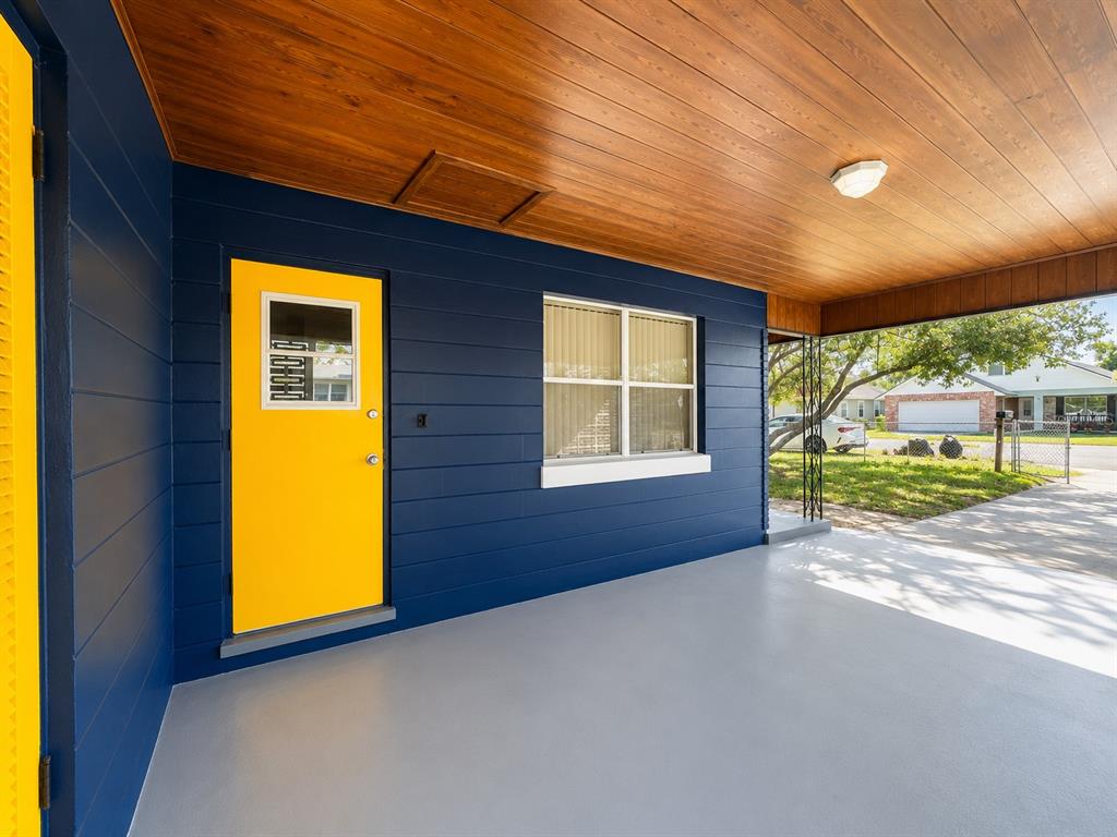 A covered porch features blue horizontal siding, a bright yellow door, and a wood-paneled ceiling — 501 AVENUE G SE, WINTER HAVEN, FL