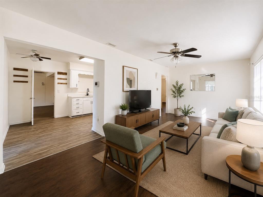 A living room with wood-look flooring, a television console, and an adjacent kitchen area — 501 AVENUE G SE, WINTER HAVEN, FL