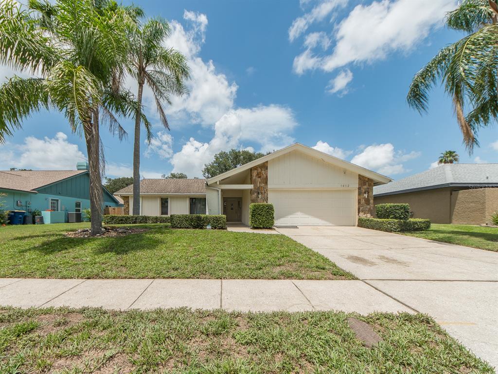 A single-story house with a two-car garage, stone accents, and palm trees in the yard — 1612 MIDNIGHT PASS WAY, CLEARWATER, FL