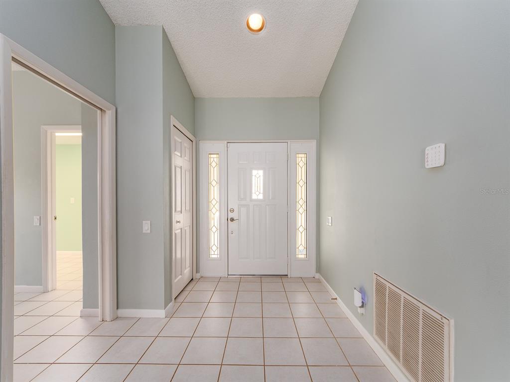A foyer features light green walls, a white front door with sidelights, and tiled flooring — 1612 MIDNIGHT PASS WAY, CLEARWATER, FL