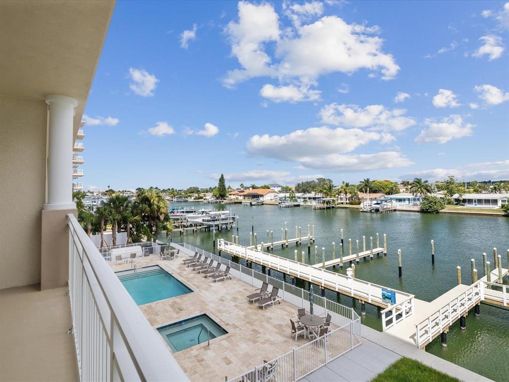 An elevated view from a balcony overlooking a swimming pool, boat docks, and a canal — 125 ISLAND WAY UNIT 305, CLEARWATER, FL
