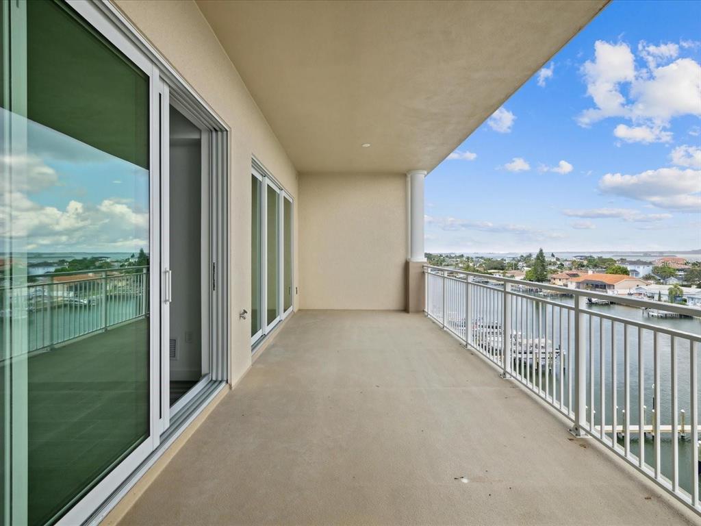 A covered balcony with a white metal railing overlooks a canal and residential neighborhood — 125 ISLAND WAY UNIT 305, CLEARWATER, FL