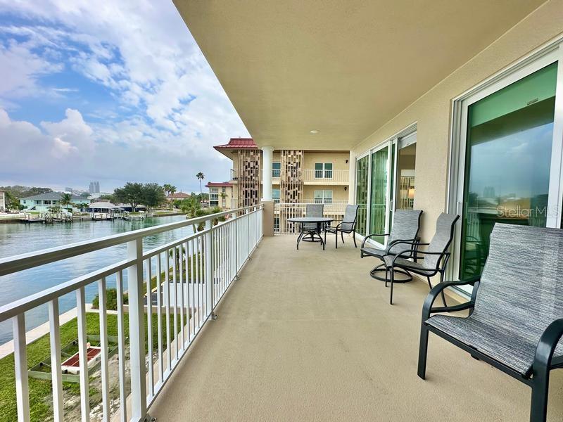 A covered balcony overlooks a waterway with outdoor furniture and white railings — 125 ISLAND WAY UNIT 305, CLEARWATER, FL