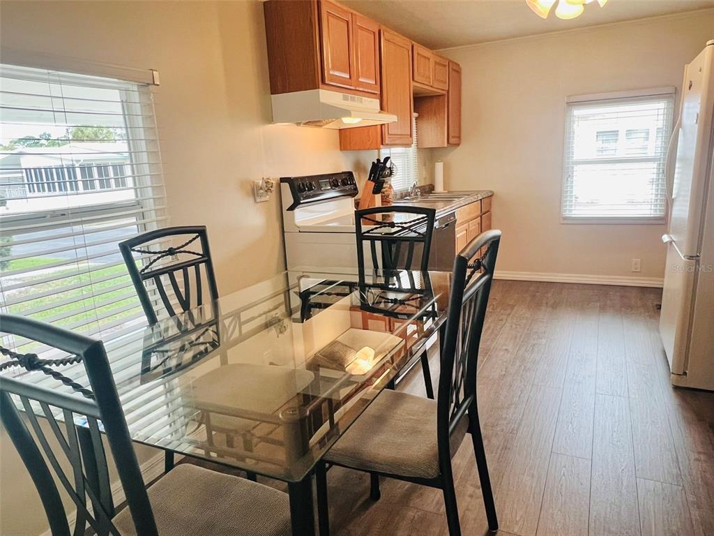 A dining area with a glass table and chairs sits adjacent to a galley kitchen — 2282 PIAZZA DRIVE UNIT 117, SARASOTA, FL