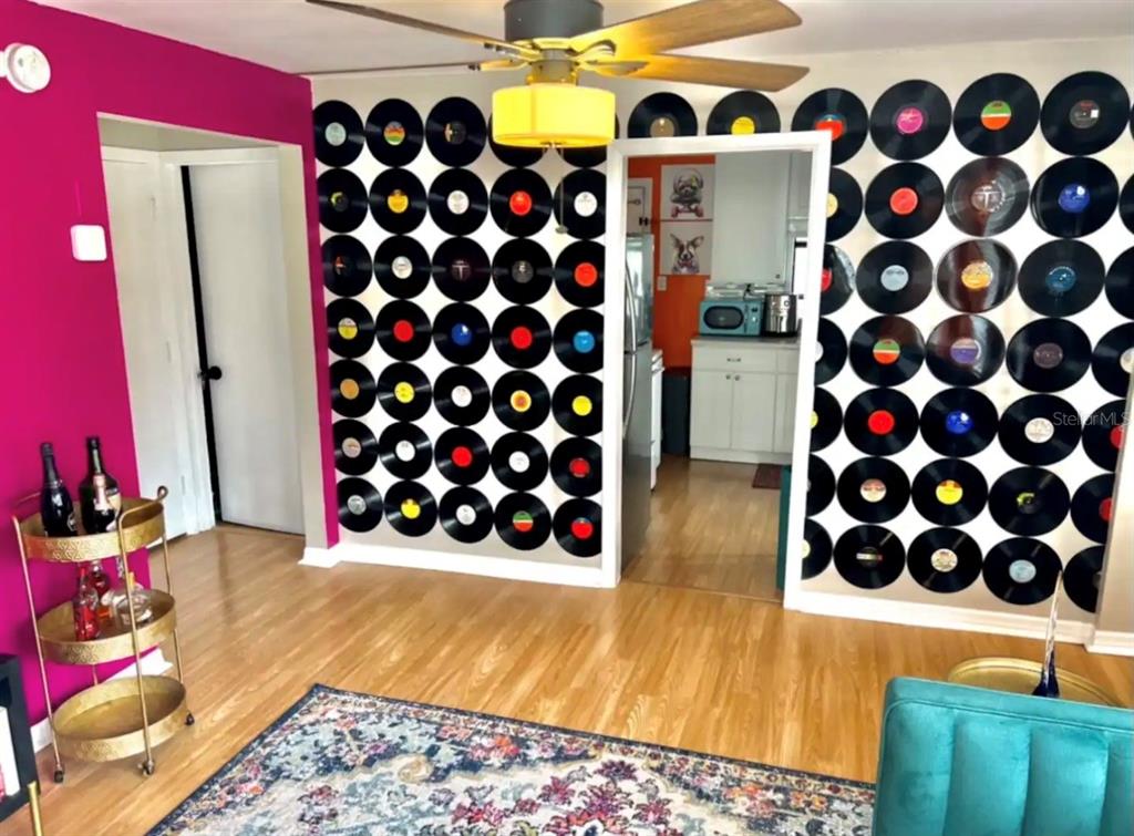 A room features a wall decorated with vinyl records, a magenta accent wall, and wood flooring — 5003 ADANSON STREET, ORLANDO, FL