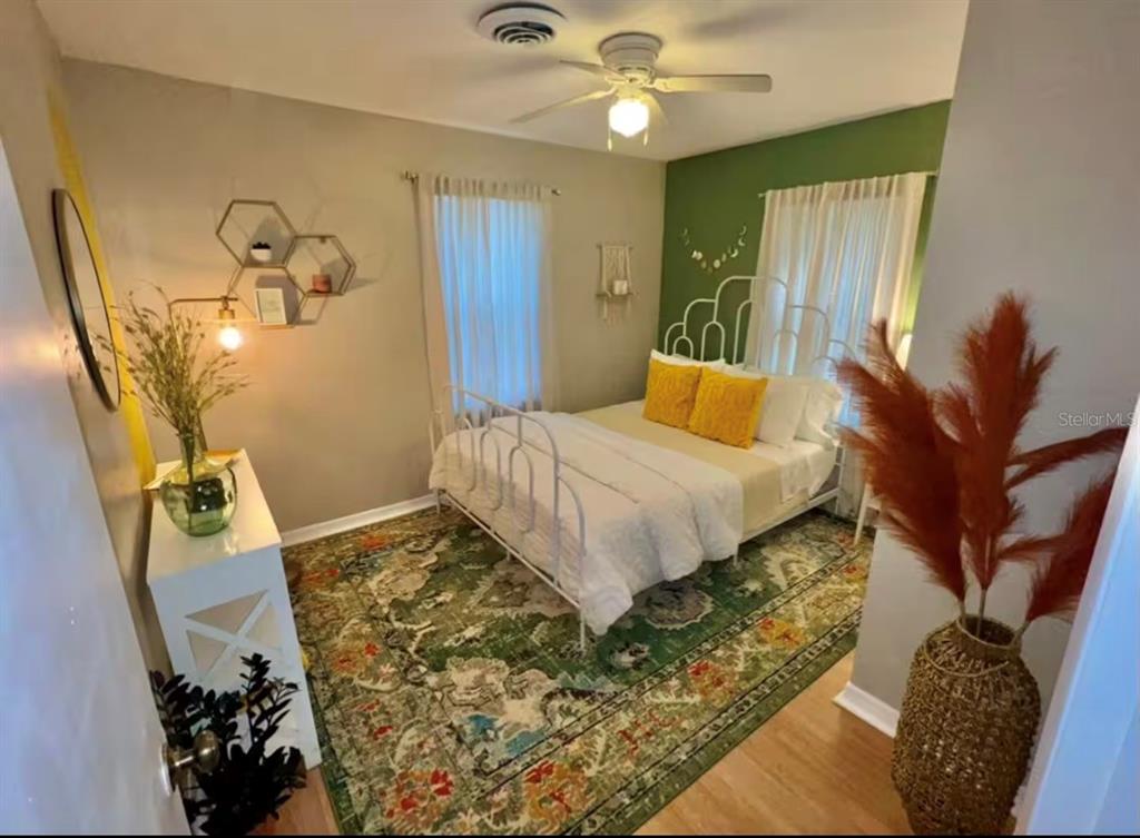 A bedroom features a white metal bed, a green accent wall, and a patterned rug — 5003 ADANSON STREET, ORLANDO, FL