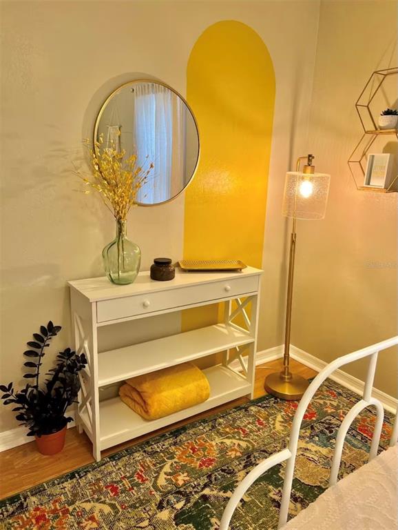 A white console table sits beneath a round mirror and a yellow painted arch — 5003 ADANSON STREET, ORLANDO, FL