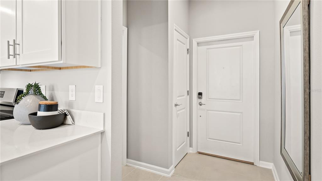 A kitchen counter with decor sits next to a white door and a wall mirror — 1812 RIDER RAIN LANE, APOPKA, FL
