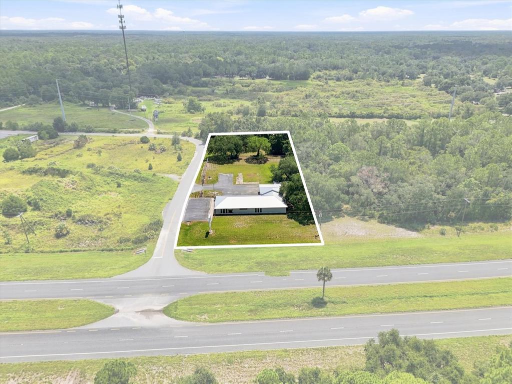 An aerial view shows a single-story building with a white roof on a grassy lot — 50 DIANA STREET, INGLIS, FL