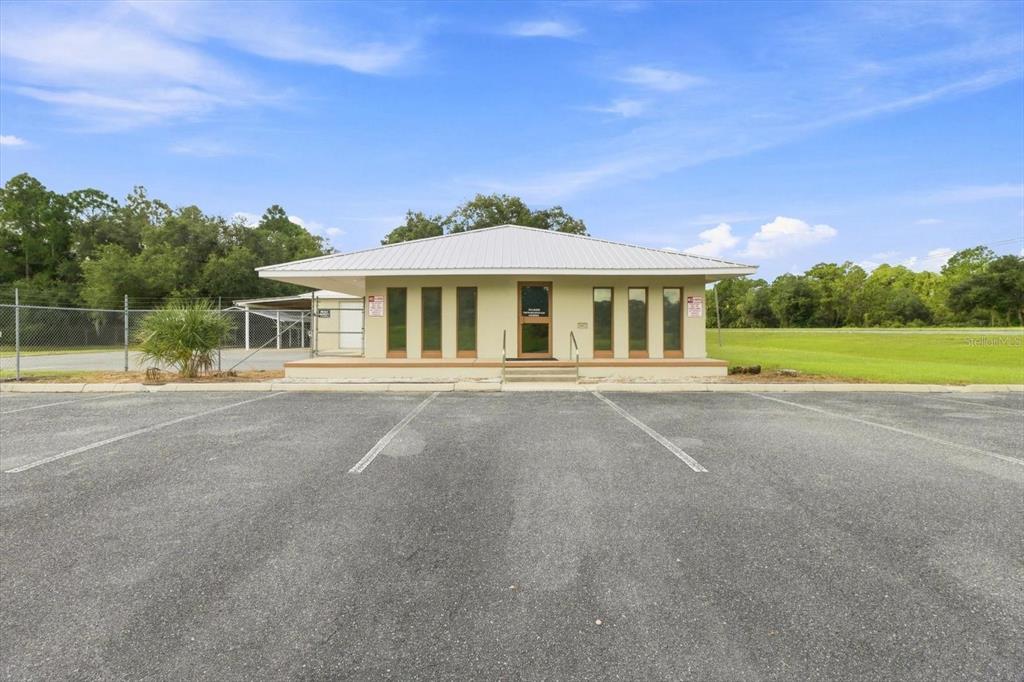 A single-story commercial building with a metal roof sits behind a paved parking lot — 50 DIANA STREET, INGLIS, FL