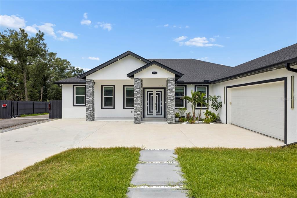 A single-story house with white stucco walls, stone pillars, and a two-car garage — 3944 WHITE HERON DRIVE, ORLANDO, FL