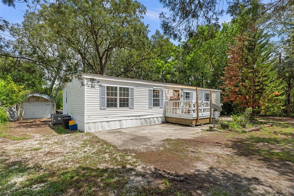 A single-story mobile home with white siding, a wooden deck, and a detached shed — 3322 SUSAN DRIVE, SPRING HILL, FL